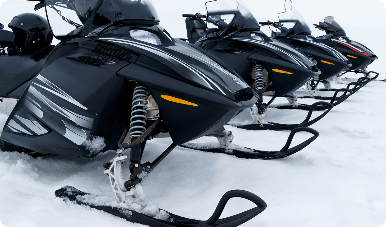 Snowmobiles lined up on snowy terrain