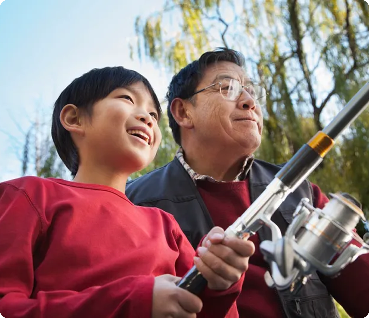 Smiling boy fishing with grandfather